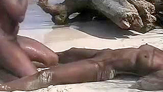 Ebony pair having a doggy style sex on the sand