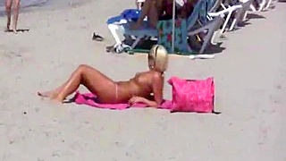 German blonde beauty gets takes care of a big cock at a topless beach