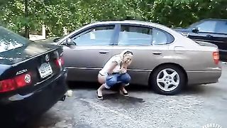 Laughing wife relieves herself in a parking lot